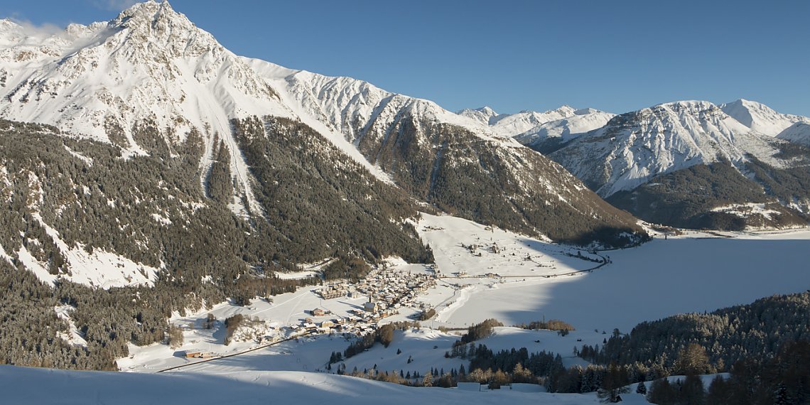 Ausblick auf den zugefrorenen Reschensee von der Reschner Alm